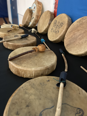 Hide drums and handmade rattles rest on a table. 