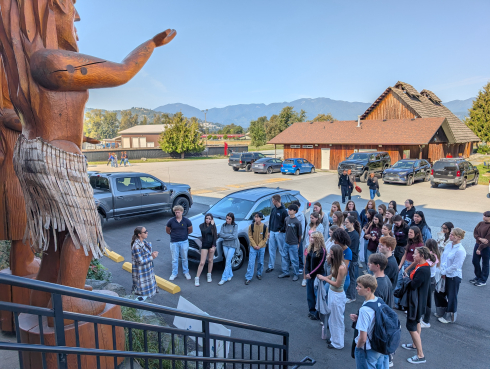 A group of students gather around carved wood figure.