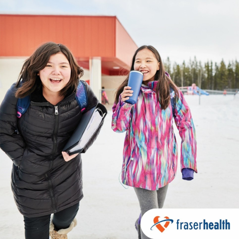 Two children are wearing winter coats and have big smiles on their faces. 