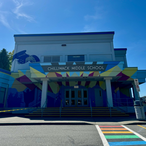 A brightly painted school with a rainbow crosswalk. 
