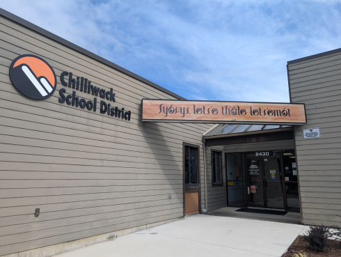 The entrance of a brown building which had a large orange, white, and black logo that reads Chilliwack School District. 