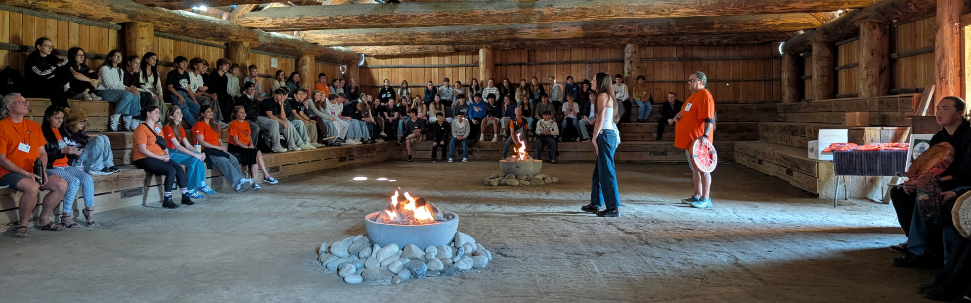 A group gathers inside a long house. 