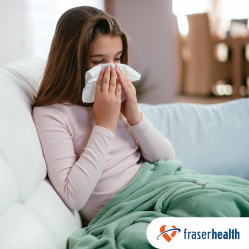 A girl on a couch uses a tissue. 