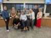 A group of people including a man using a wheelchair are gathered together and posing for a picture. 