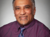 A photo of a man wearing a purple shirt and striped tie. 