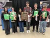 A group of students display their ribbons and awards in front of science banners.