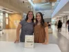 Two teachers smile at the camera. On a white table in front of them a sign reads "Meet the teachers". 