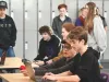 A group of students and an adult work on computers. 