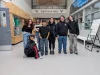 A group of students gather in the hallway of their school. They are smiling. 