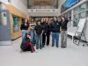 A group of students gather with a teacher in the hallway of their school. They are smiling. 
